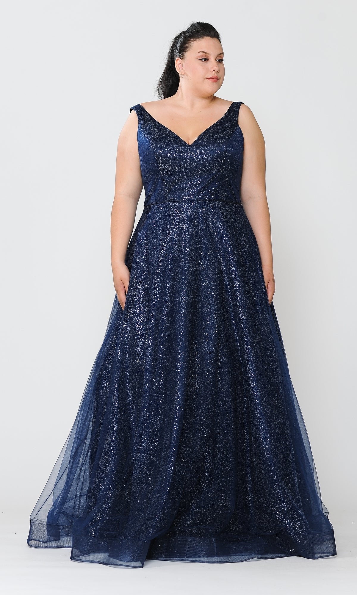 A woman models the Glitter-Tulle Plus-Size Long Prom Gown W1024, a sleeveless navy blue evening dress with a V-neckline, standing against a plain white background.
